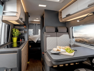KNAUS BOXLIFE PLATINUM SELECTION 2027 – Wohnbereich mit Sitzgruppe Innenraum des KNAUS BOXLIFE PLATINUM SELECTION 2027 mit Sitzgruppe, Esstisch, Küchenzeile und Blick zum Heckbett